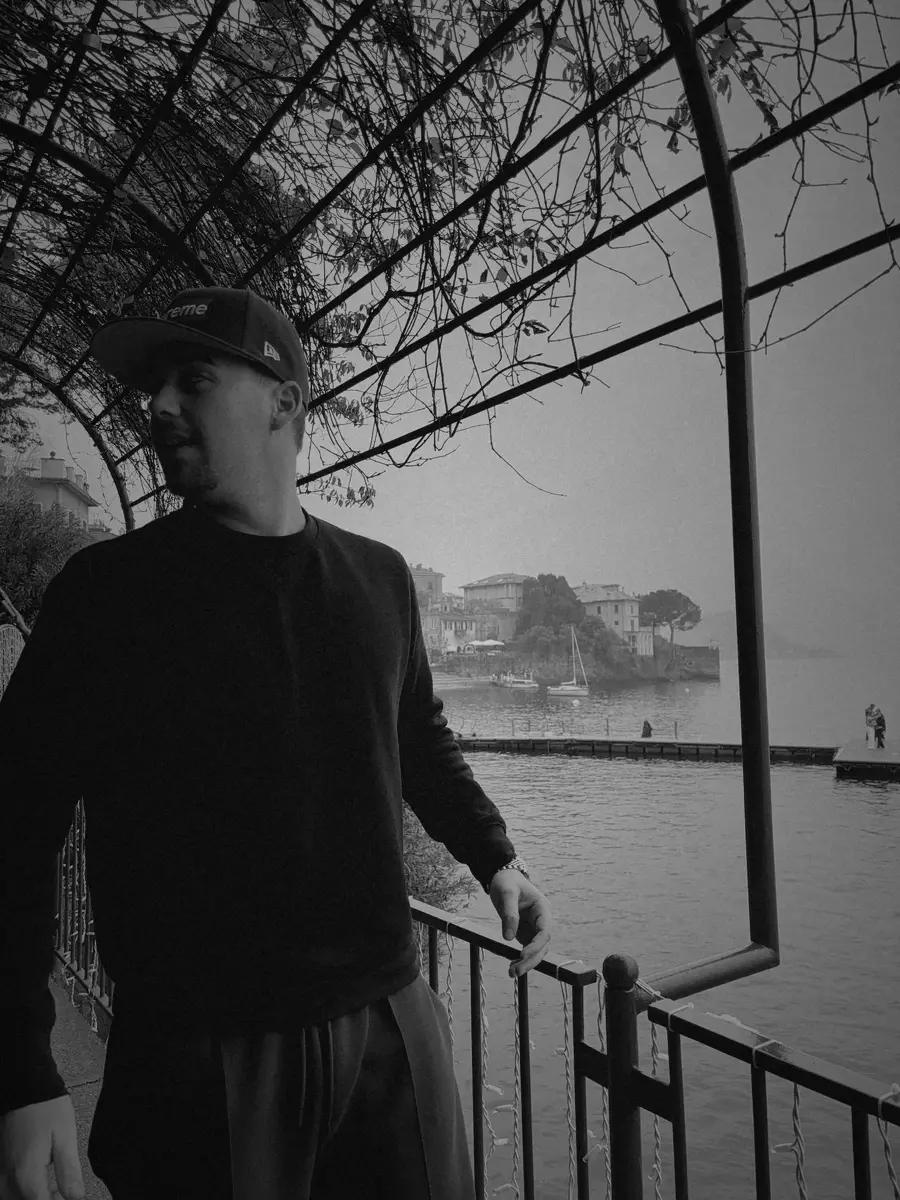 Black and white photo of Valentín on a balcony by a lake.