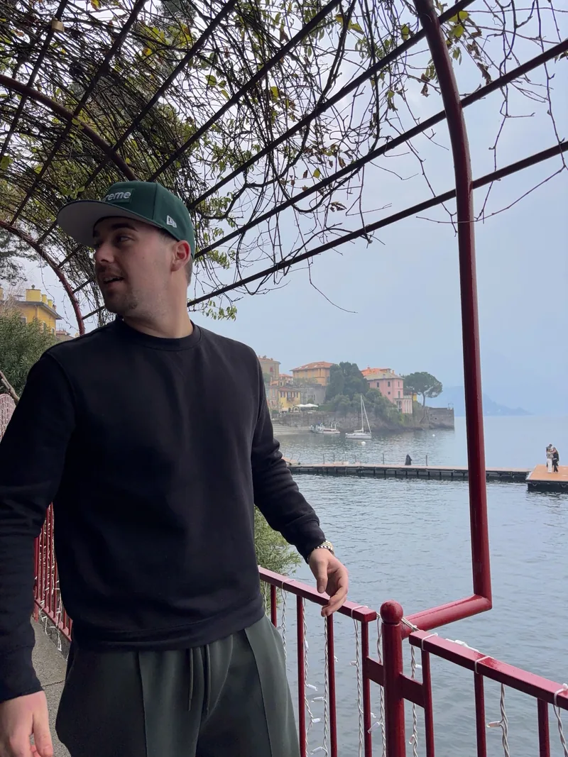 Valentín on a balcony with a red railing, Lake Como behind him.