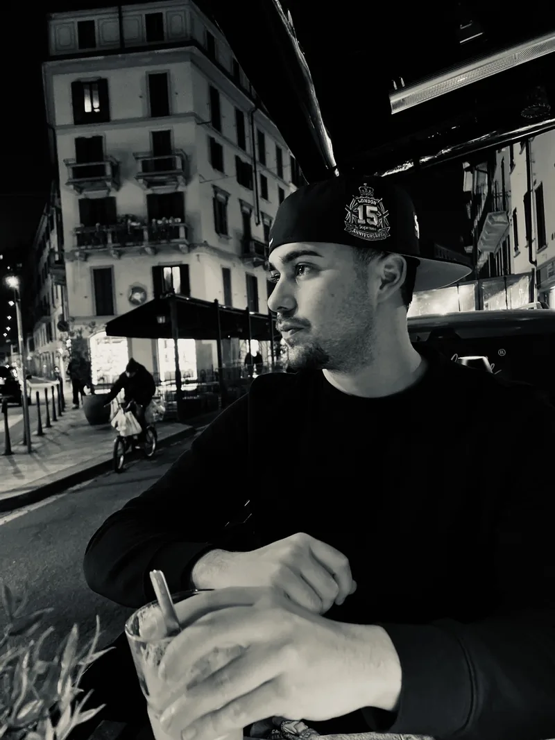 Black and white photo of Valentín in a cap at a café table at night.