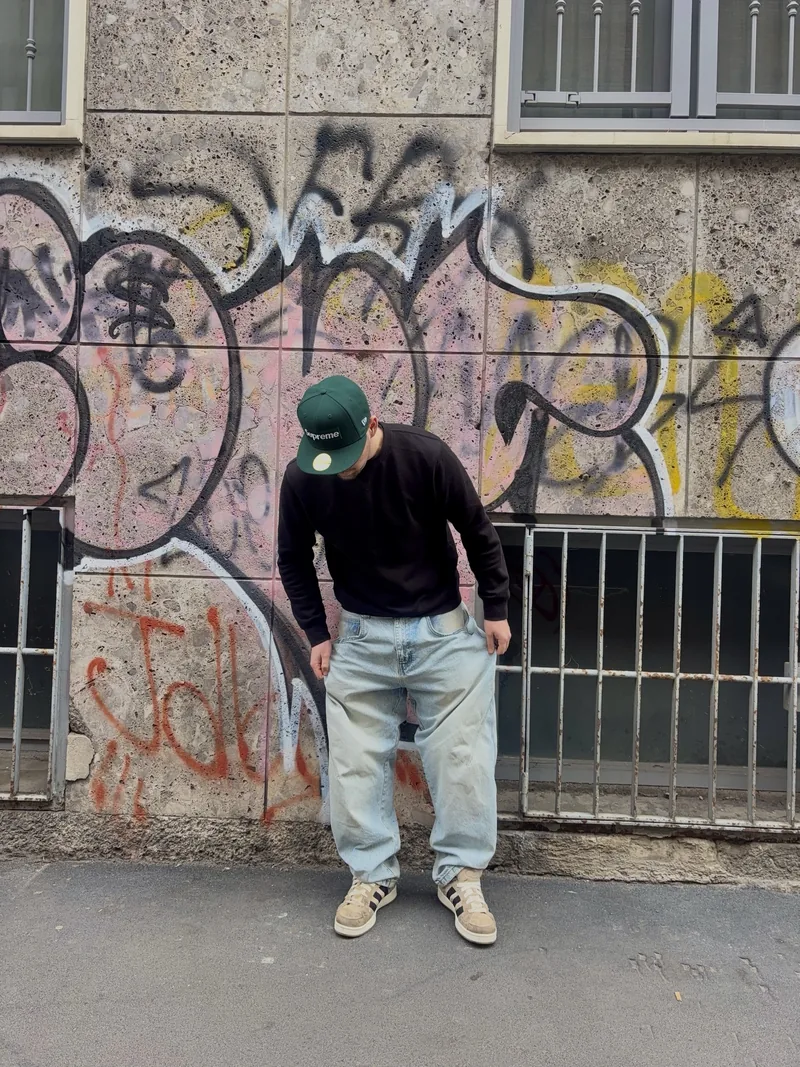 Valentín leaning forward in front of the same graffiti wall.